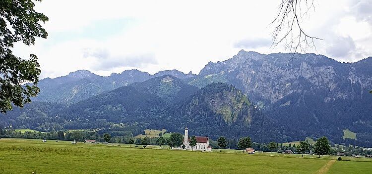 Kirche im Feld mit Bergen im Hintergrund